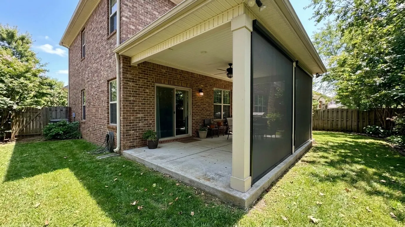 After: a covered backyard patio with charcoal retractable screens lowered between the columns