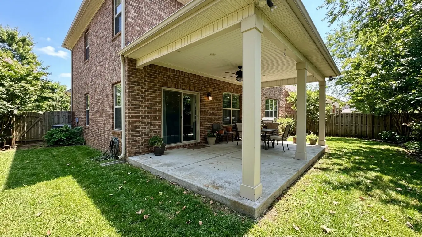 Before: a covered backyard patio with an open covered patio with two brick columns and no screens
